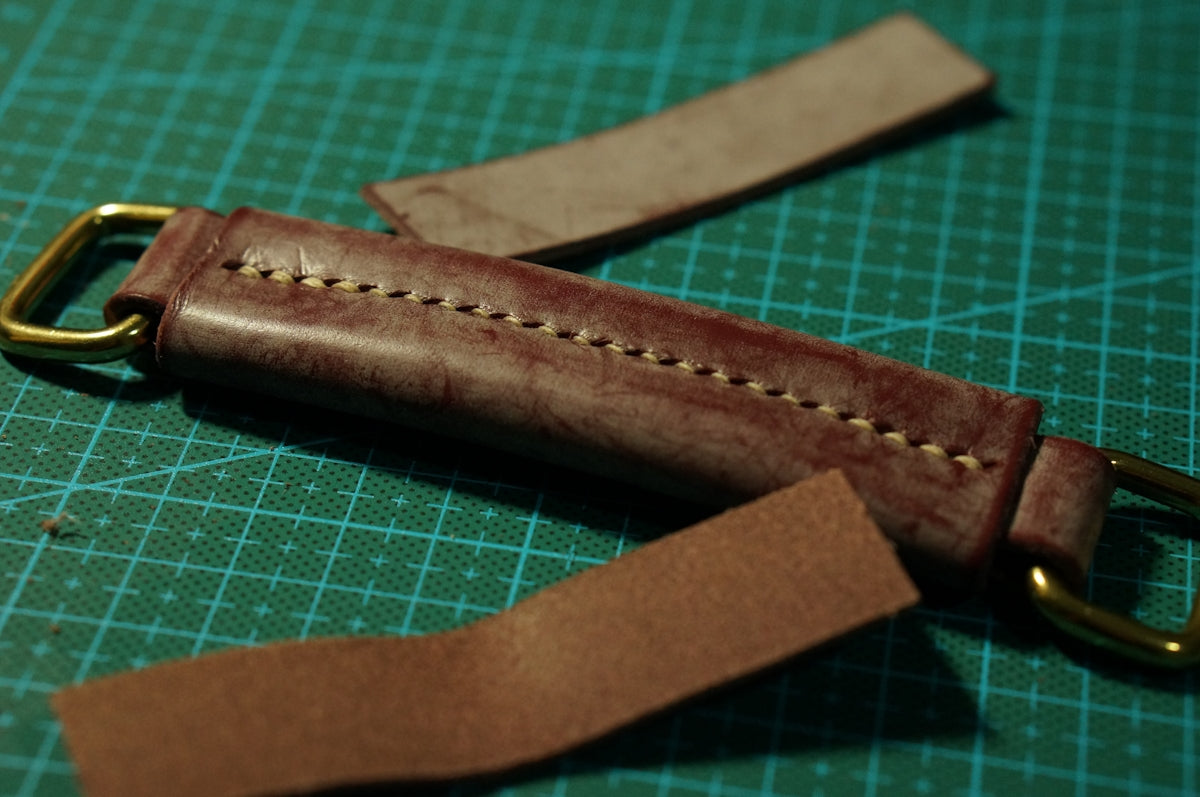 a leather watch strap on a green cutting mat