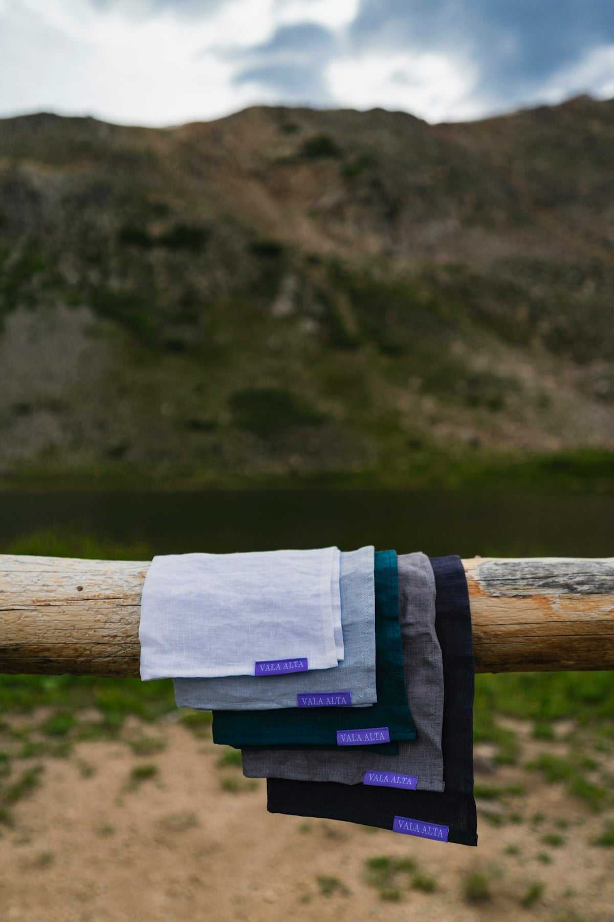 Handmade belts in USA displayed outdoors on wooden rail with mountain background