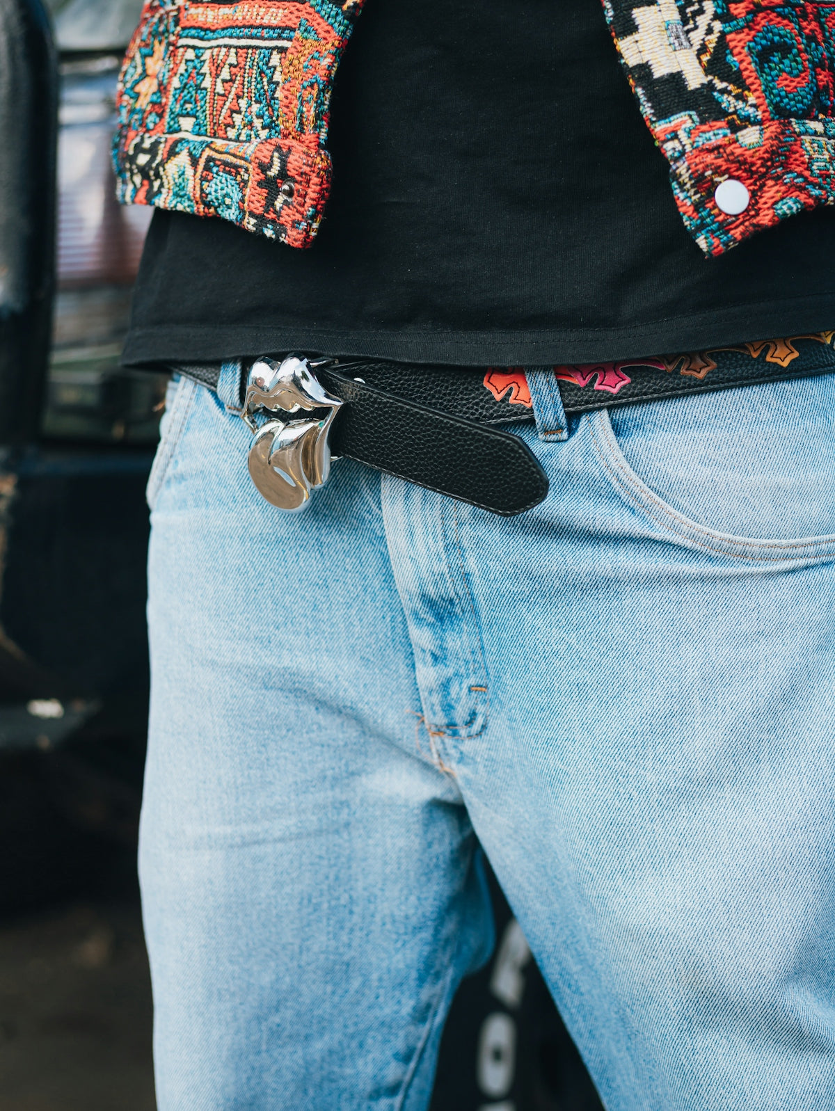 Person wearing a colorful jacket, black shirt, and jeans.