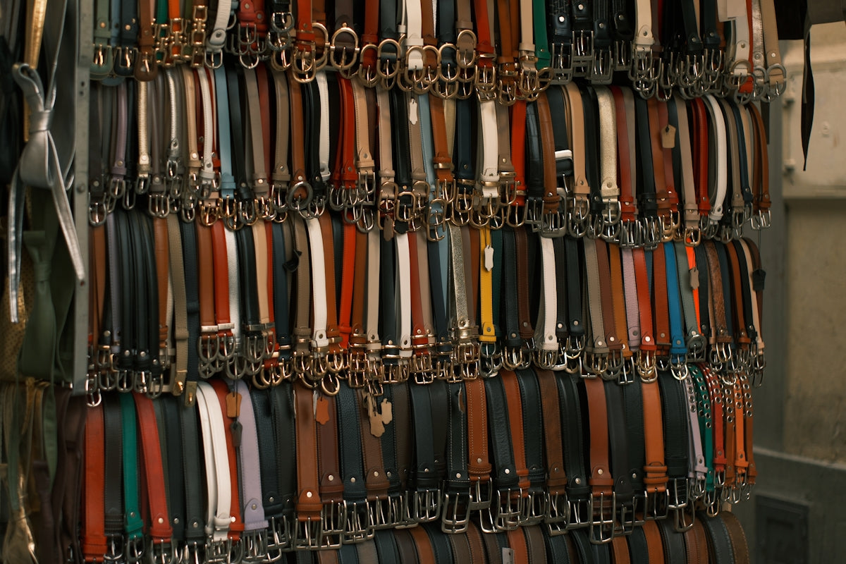 Wall of many colorful leather belts with buckles.