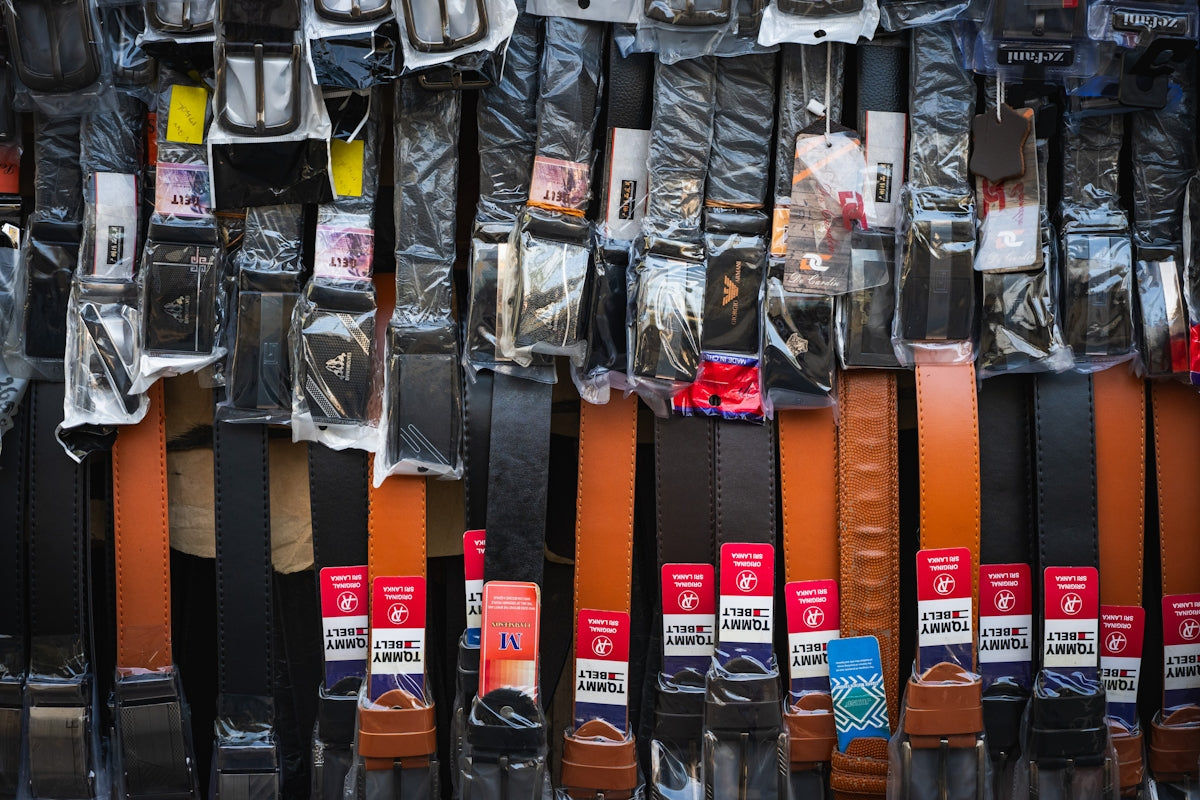 Many belts hanging vertically in a market stall.
