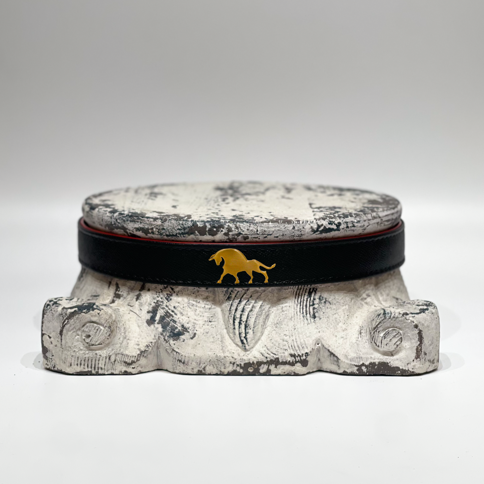 Bos Belt Black handmade black leather belt with matte brass buckle and embossed horse design on decorative stone pedestal